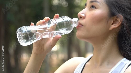 Zoom out slow motion camera panning and focus at young woman drink water from a plastic bottle