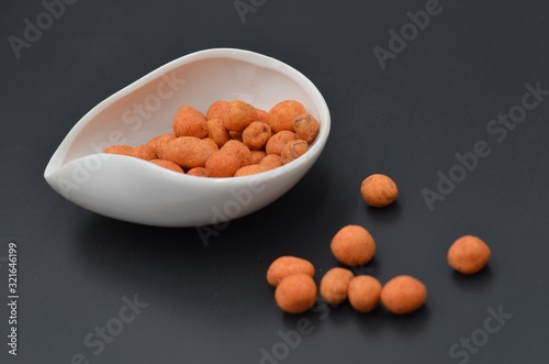 Peanut snacks on a white disk on a black background