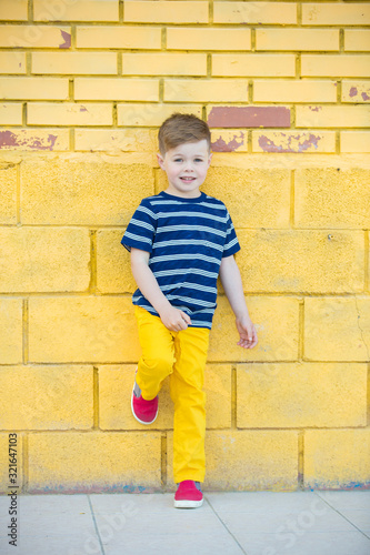 Little boy posing against the wall