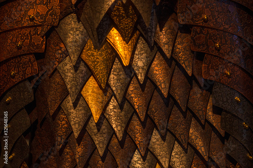 Metal scales of different shades close up. Background with golden rhombuses. Neutral dark background.