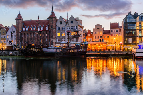 Sightseeing of Poland. Cityscape of Gdansk in the night. Facades of buildings and a ship on the motlava river with illumination
