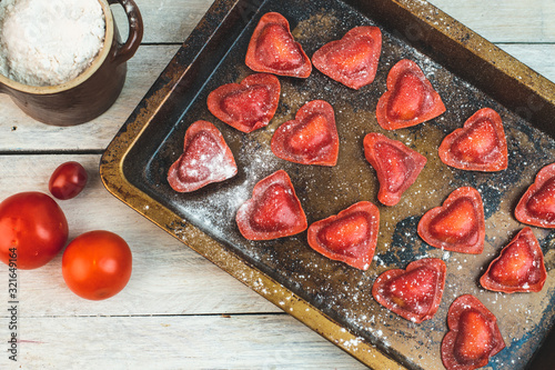 Photography red heart-shaped tomato ravioli on an old baking sheet