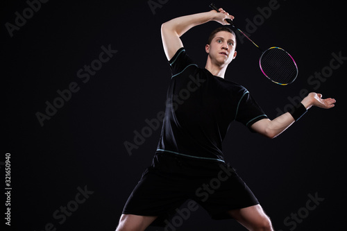 Badminton player in sportswear with racket and shuttlecock on black background. © Mike Orlov
