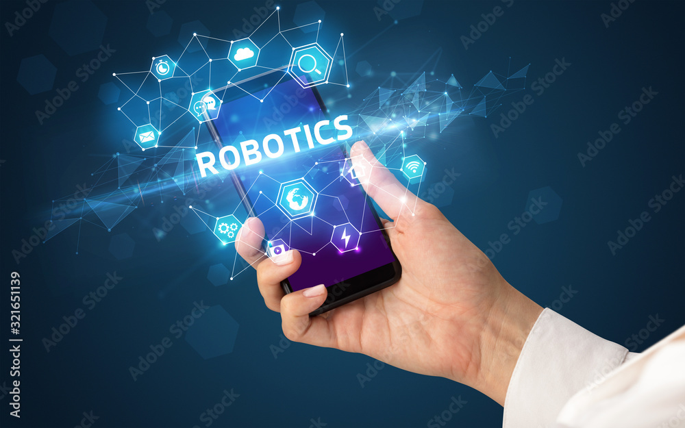Female hand holding smartphone with ROBOTICS inscription, modern technology concept Female hand holding smartphone with ROBOTICS inscription, modern technology concept
