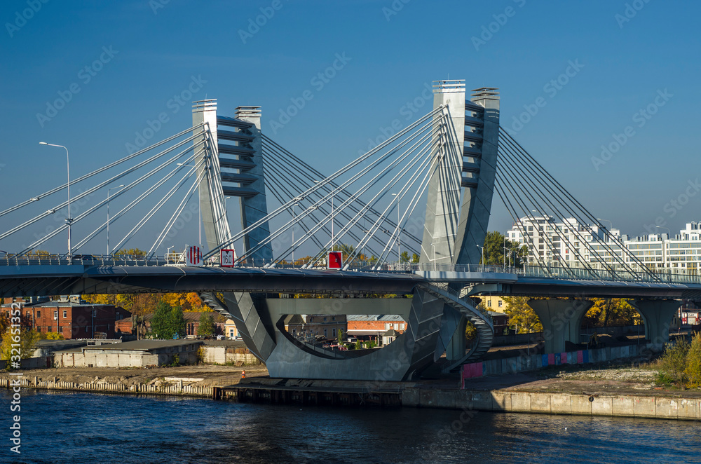 Obraz premium New cable-stayed automobile city bridge with blue expanse of water, blue sky. Betancourt Bridge. Panorama of a modern city. View of the Petrovsky island of St. Petersburg, Russia, May 1, 2019