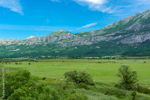 Landscape of a valley and low mountains in the Dalmatian region with farms and villages.