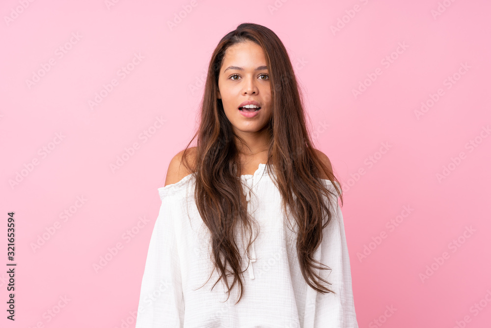 Young Brazilian girl over isolated pink background with surprise facial expression Young Brazilian girl over isolated pink background with surprise facial expression