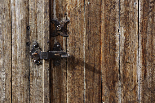 Old iron lock and latch on aged boarded door.