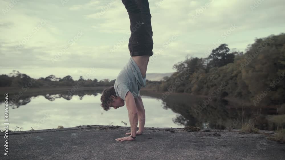 Athletic man performs handstand strength exercise breathtaking view