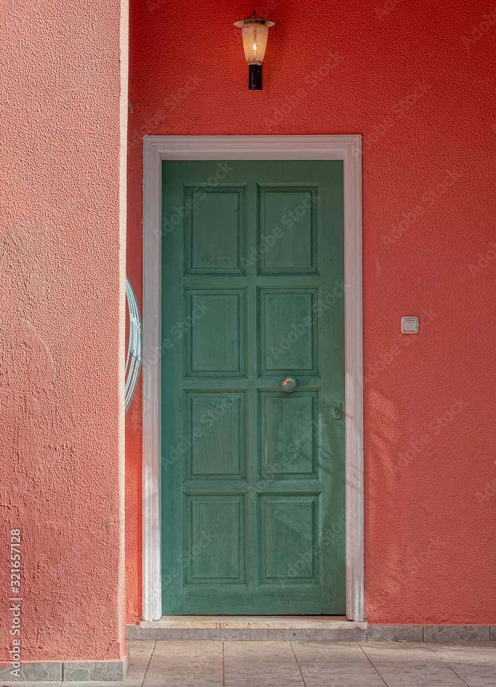 Naklejka premium colorful house entrance green wooden door on redish wall, Athens Greece
