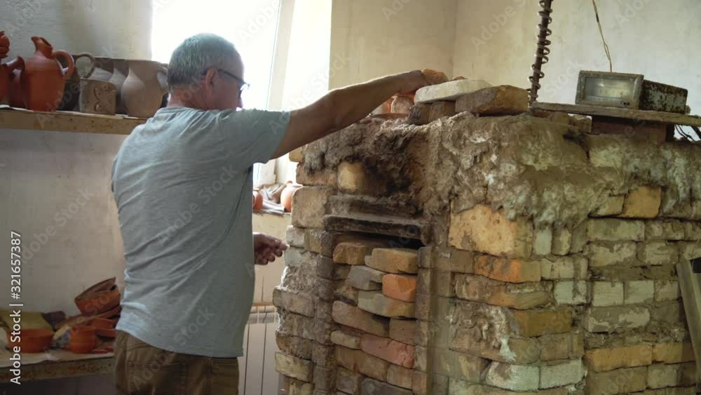Potter prepares brick pottery oven for work in authentic workshop. Potter prepares brick pottery oven for work in authentic workshop.
