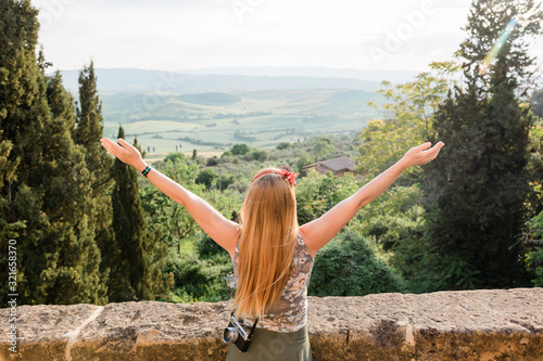Young woman standing with her arms stretched enjoying the view of the Tuscany landscape