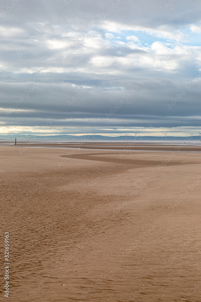 The vast empty beach at Formby in Merseyside, with an offshore windfarm visible in the sea
