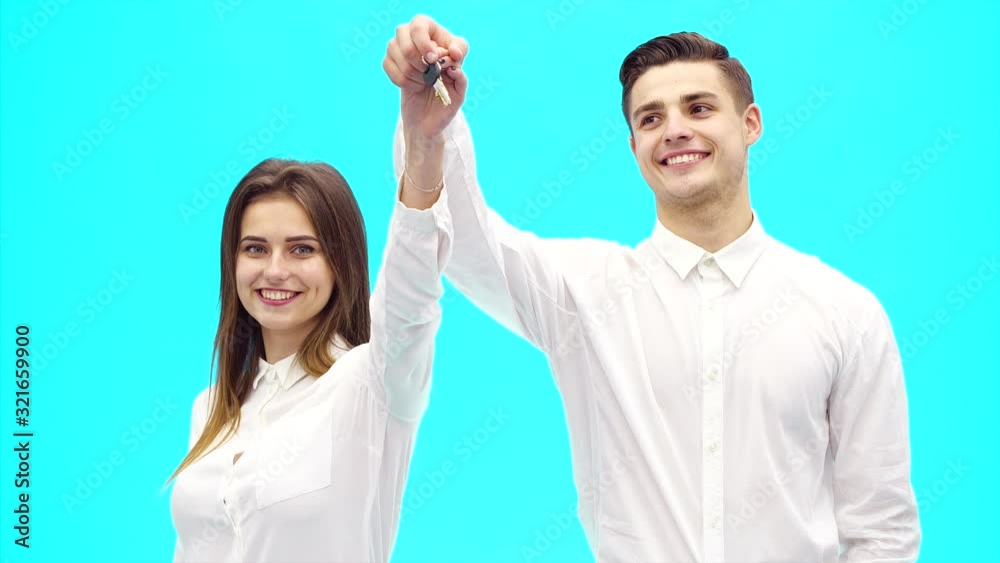 Business couple shows the key from new office. Successful agreement. They are smiling widely. Close up. Copy space. 4K. Business couple shows the key from new office. Successful agreement. They are smiling widely. Close up. Copy space. 4K.