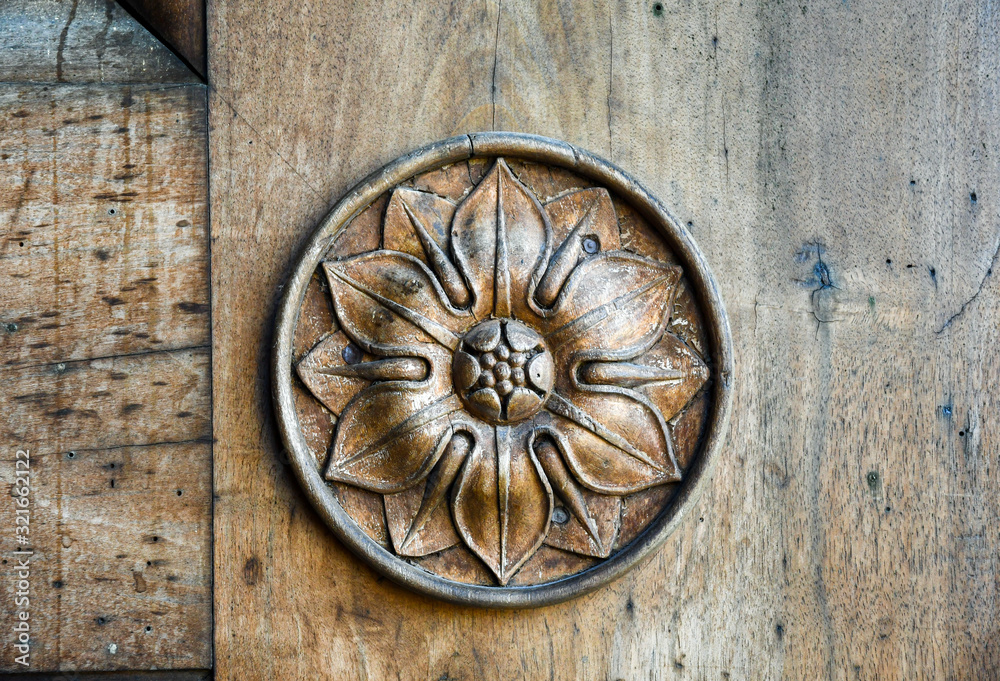 Close-up of an old wooden door with carved circular floral decoration, Italy Close-up of an old wooden door with carved circular floral decoration, Italy