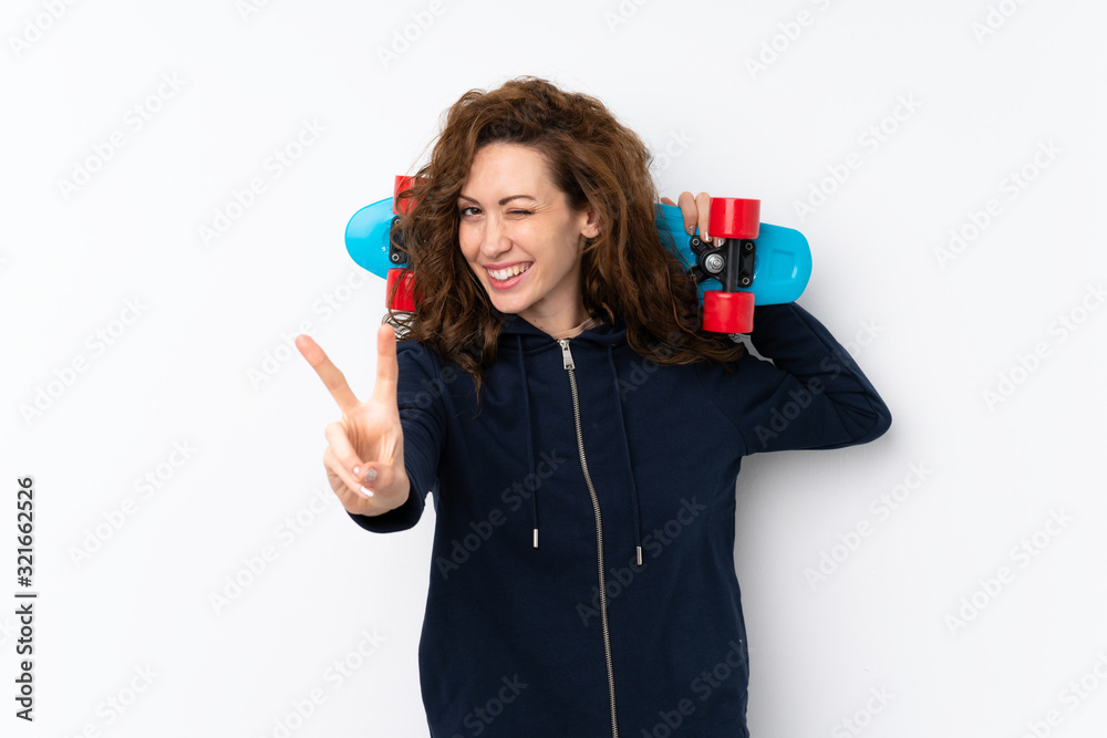 Young pretty woman over isolated background with skate and making victory gesture Young pretty woman over isolated background with skate and making victory gesture