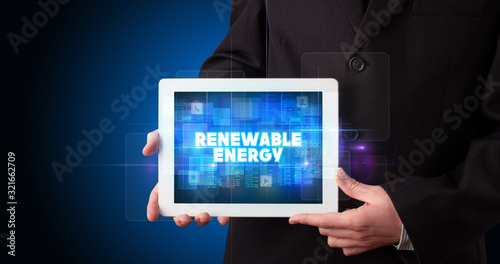 Wallpaper Mural Young business person working on tablet and shows the inscription: RENEWABLE ENERGY Torontodigital.ca