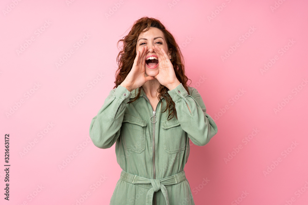 Young pretty woman over isolated pink background shouting and announcing something Young pretty woman over isolated pink background shouting and announcing something
