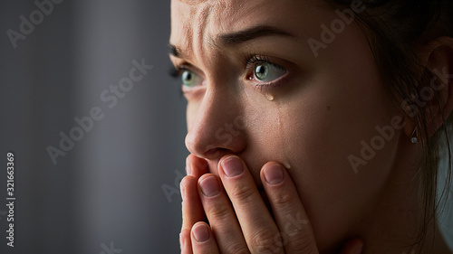 Foto Sad desperate grieving crying woman with folded hands and tears eyes during trou