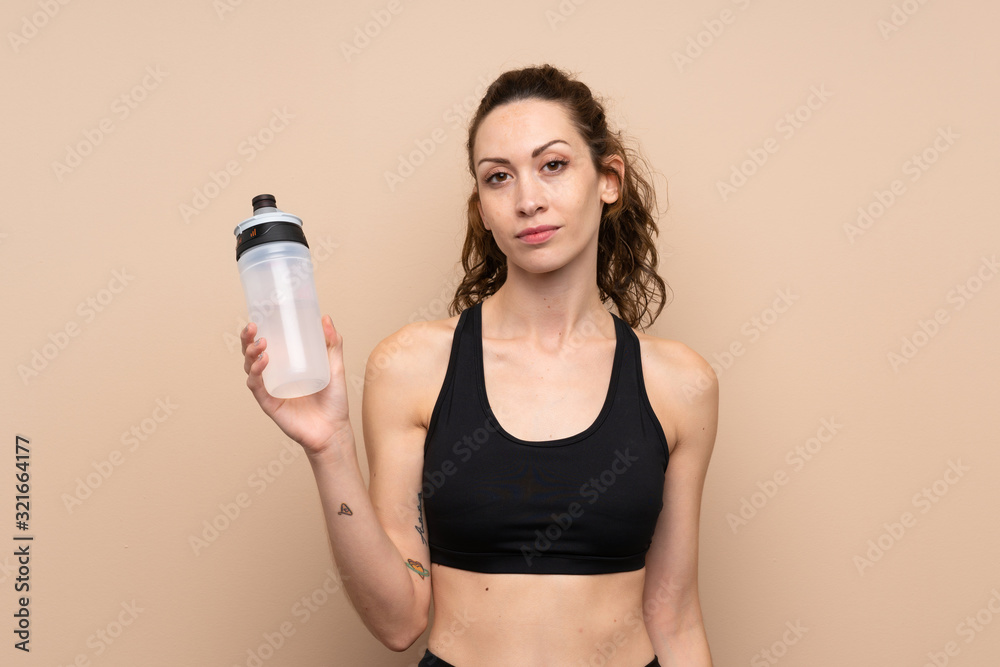 Young sport woman over isolated background with sports water bottle