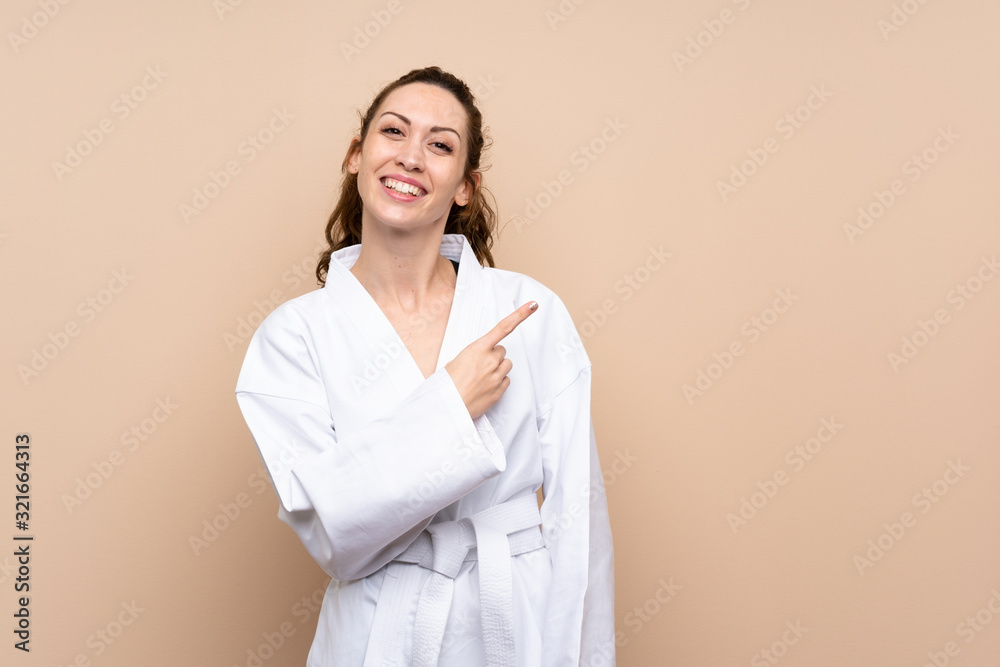 Young woman doing karate pointing to the side to present a product Young woman doing karate pointing to the side to present a product