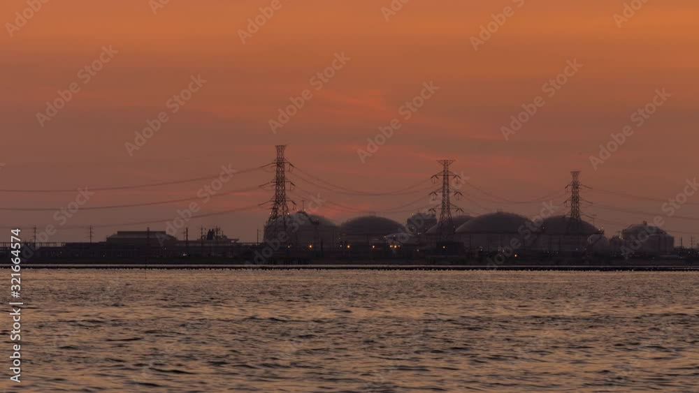 time lapse of sunset behind oil and gas refinery and tank farm from international shipping harbor and trading energy for petrochemical industry to drive business in logistic and energy time lapse of sunset behind oil and gas refinery and tank farm from international shipping harbor and trading energy for petrochemical industry to drive business in logistic and energy