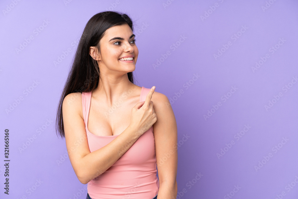 Young woman over isolated purple background surprised and pointing side Young woman over isolated purple background surprised and pointing side