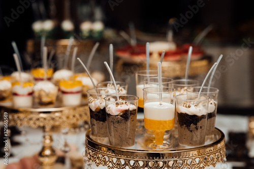 Glasses with healthy layered dessert white chia seeds pudding, mango, blueberries, coconut flakes with bottle of milk, seeds. Wedding banquet table
