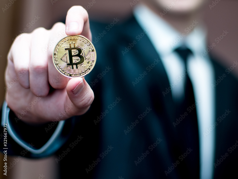 Male hand hold bitcoin. Businessman in suit show bit coin. Stock photo with flare. Cryptography concept