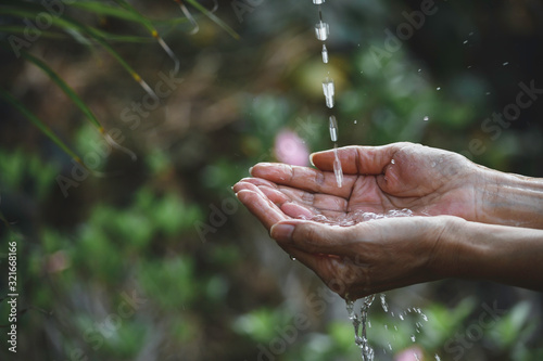 Closeup water flow to hand of women for nature concept on the garden background.