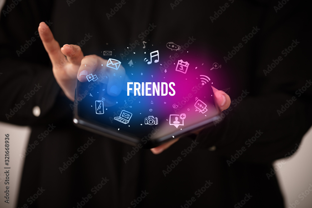 Businessman holding a foldable smartphone with FRIENDS inscription, social media concept Businessman holding a foldable smartphone with FRIENDS inscription, social media concept