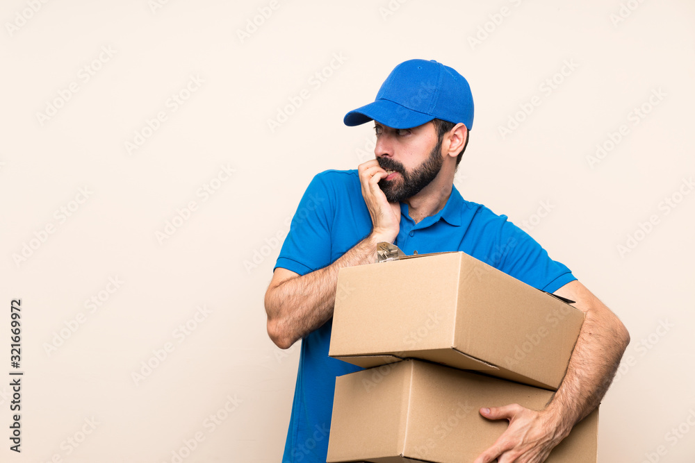 Delivery man with beard over isolated background nervous and scared putting hands to mouth Delivery man with beard over isolated background nervous and scared putting hands to mouth