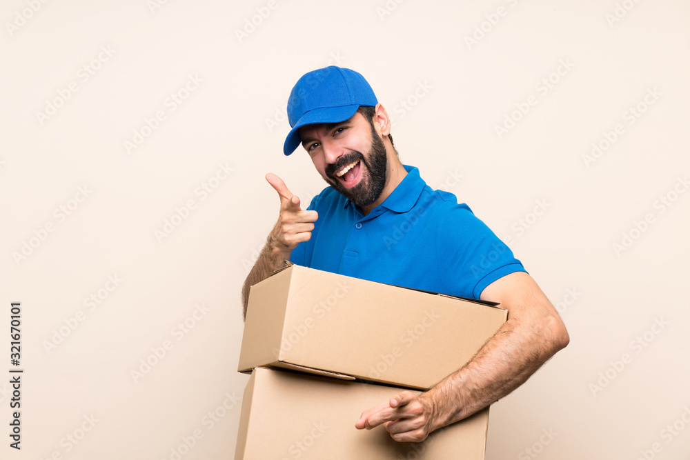 Delivery man with beard over isolated background points finger at you while smiling Delivery man with beard over isolated background points finger at you while smiling