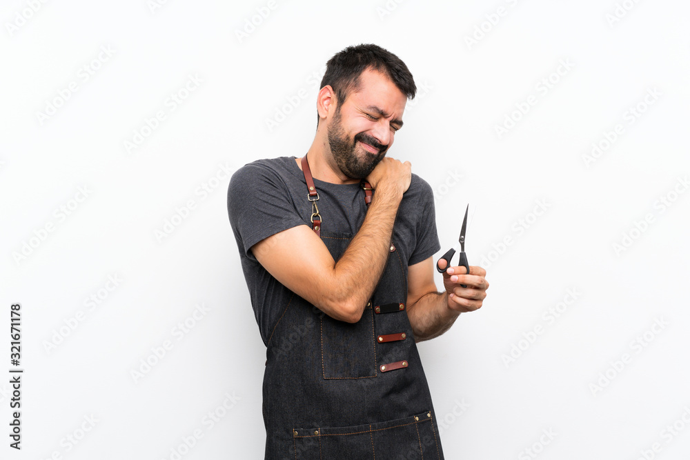 Barber man in an apron suffering from pain in shoulder for having made an effort Barber man in an apron suffering from pain in shoulder for having made an effort