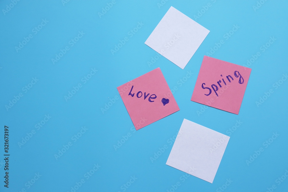 leaves with the inscriptions love, spring on a blue background. copy space leaves with the inscriptions love, spring on a blue background. copy space