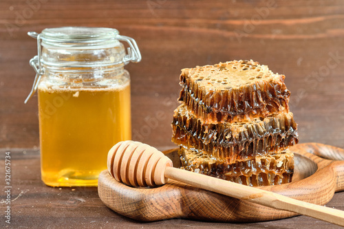 honey in honeycombs on a wooden plate and golden honey in jars with nuts