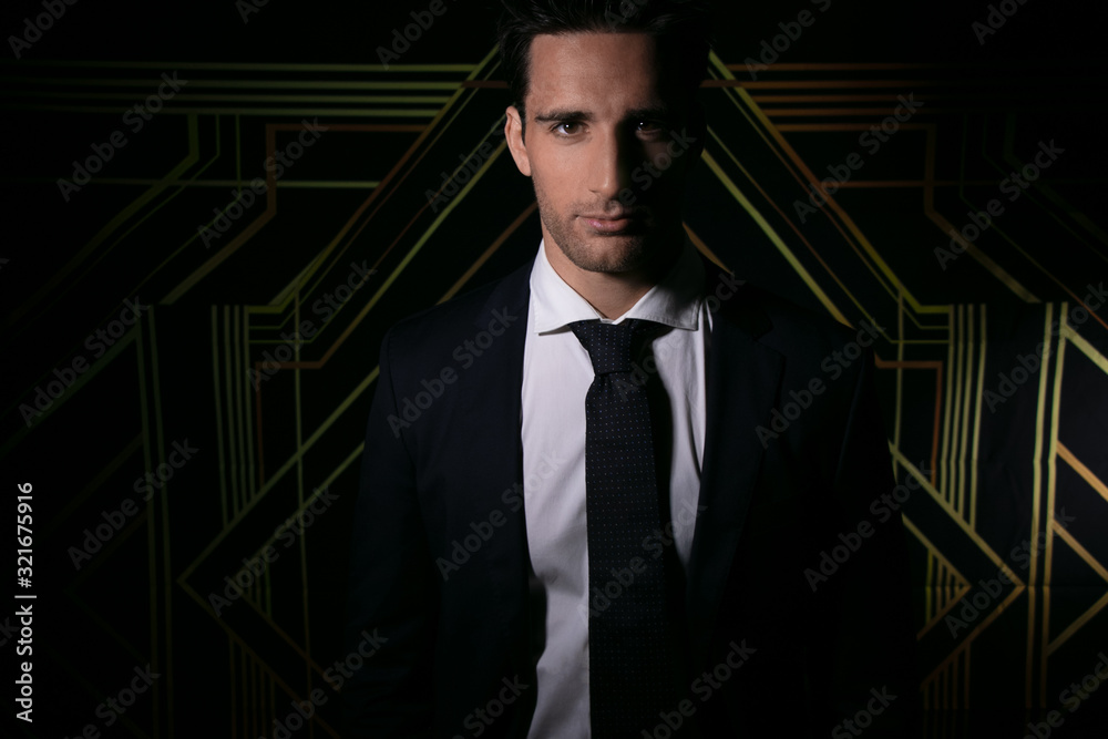 Fototapeta premium Handsome man in suit and tie in front of art deco backdrop smiling at camera