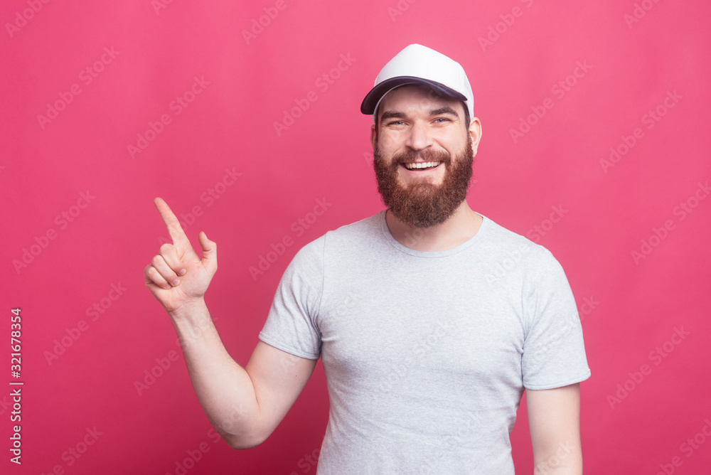 Joyful handsome man pointing at copyspace over pink background