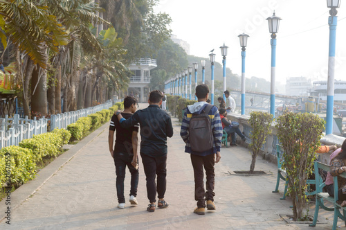 Friends walking along the promenade in street footpath on a quiet and relaxed evening in Millennium Eco Tourism Park and Recreational Riverside Beautification area. Kolkata India Asia Pac May 2019.