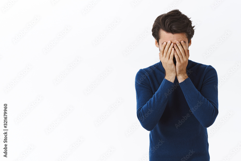 Distressed, tired businessman in blue high neck sweater, hiding face, facepalm, holding hands on head and sighing, feeling troubled, exhausted as working hard during holidays, stand white background Distressed, tired businessman in blue high neck sweater, hiding face, facepalm, holding hands on head and sighing, feeling troubled, exhausted as working hard during holidays, stand white background