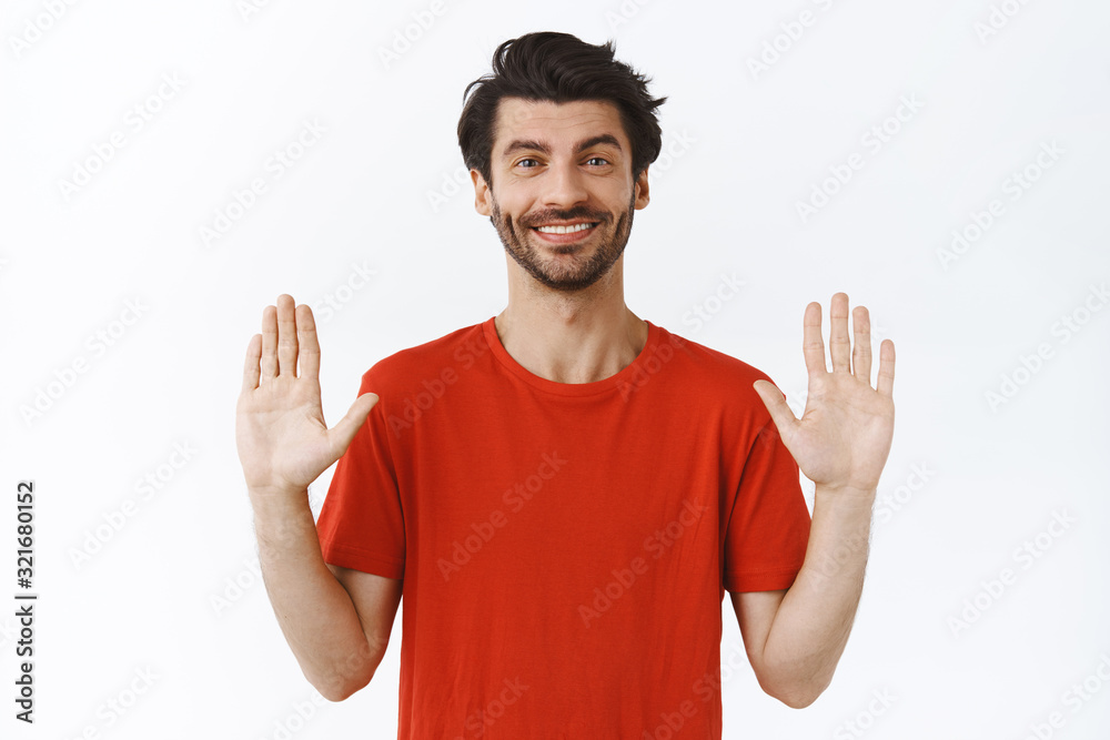 Relax, everything under control. Confident good-looking bearded guy in red t-shirt, raising hands up and smiling, asking keep calm, rejecting something politely, standing white background Relax, everything under control. Confident good-looking bearded guy in red t-shirt, raising hands up and smiling, asking keep calm, rejecting something politely, standing white background