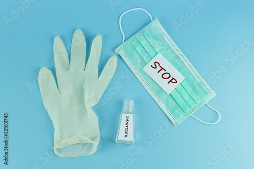Protective face mask, sanitizer gel dispenser and medical glove on blue background, against Novel coronavirus (2019-nCoV) or Wuhan coronavirus and Influenza. Antiseptic, Hygiene and Healthcare concept