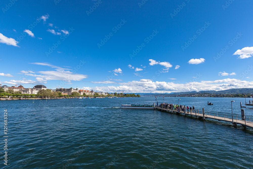 Panorama view of the Zurichsee (Zurich lake) and the cityscape of old town with Swiss Alps mountain range and blue sky cloud in background on a sunny summer day, Zurich, Switzerland