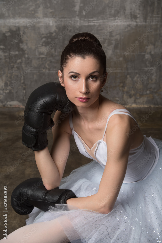 Portrait of russian ballerina in white costume wearing boxing gloves