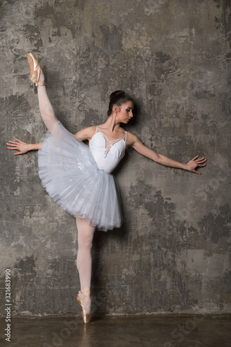 Ballerina doing the splits near gray wall
