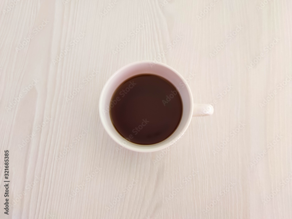 A white cup of tea or coffee and saucer on the wooden table with copy space. A photo for a café or restaurant menu or package backdrop. A white cup of tea or coffee and saucer on the wooden table with copy space. A photo for a café or restaurant menu or package backdrop.
