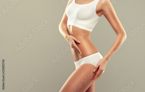  Perfect slim toned young body of the girl . An example of sports , fitness or plastic surgery and aesthetic cosmetology.