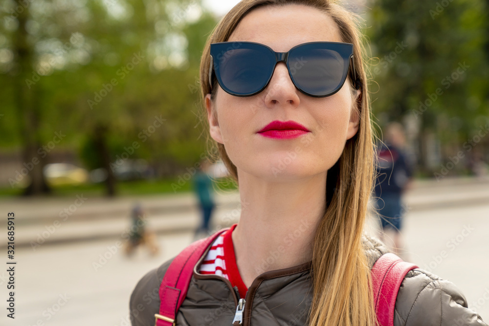 Portrait of a young city women - long blond hair, bright pink lips, stylish sunglasses. Spring mood on the street. Blurred urban city background, closeup, copy space. Portrait of a young city women - long blond hair, bright pink lips, stylish sunglasses. Spring mood on the street. Blurred urban city background, closeup, copy space.