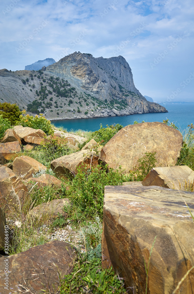Boulders on the cape and a magical view of the mountains and the Black Sea. Blue Bay in the New World Botanical Reserve, Crimea
