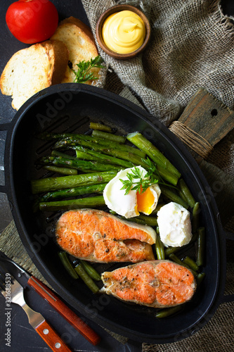 Green asparagus, grilled salmon and poached eggs. Healthy food on rustic wooden background. Top view flat lay background.